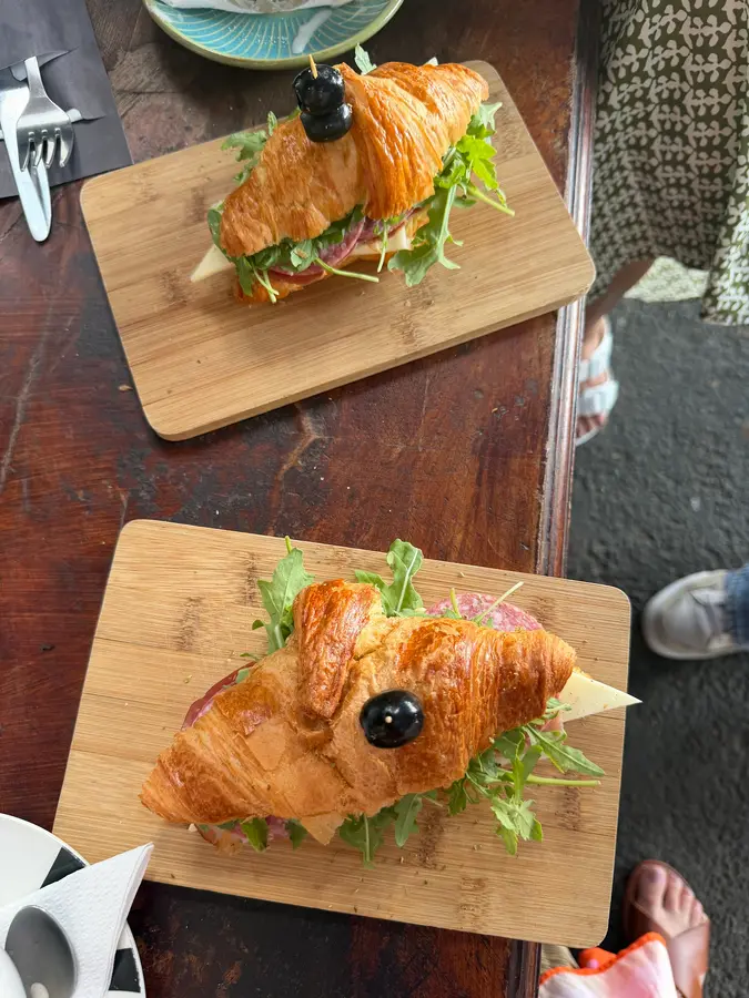 Zwei belegte Croissants mit Rucola auf Holzbrettern