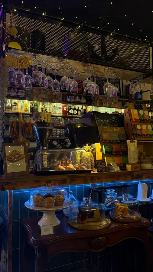 Die Bar am Abend mit Gläsern, Kuchen unter Glashauben und blau beleuchteten Fliesen
