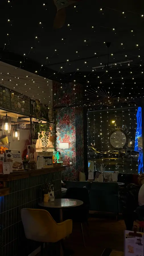 Das Café am Abend: Lichterketten an der Decke wie ein Sternenhimmel, Blätter-Tapete, grüne Fliesen
